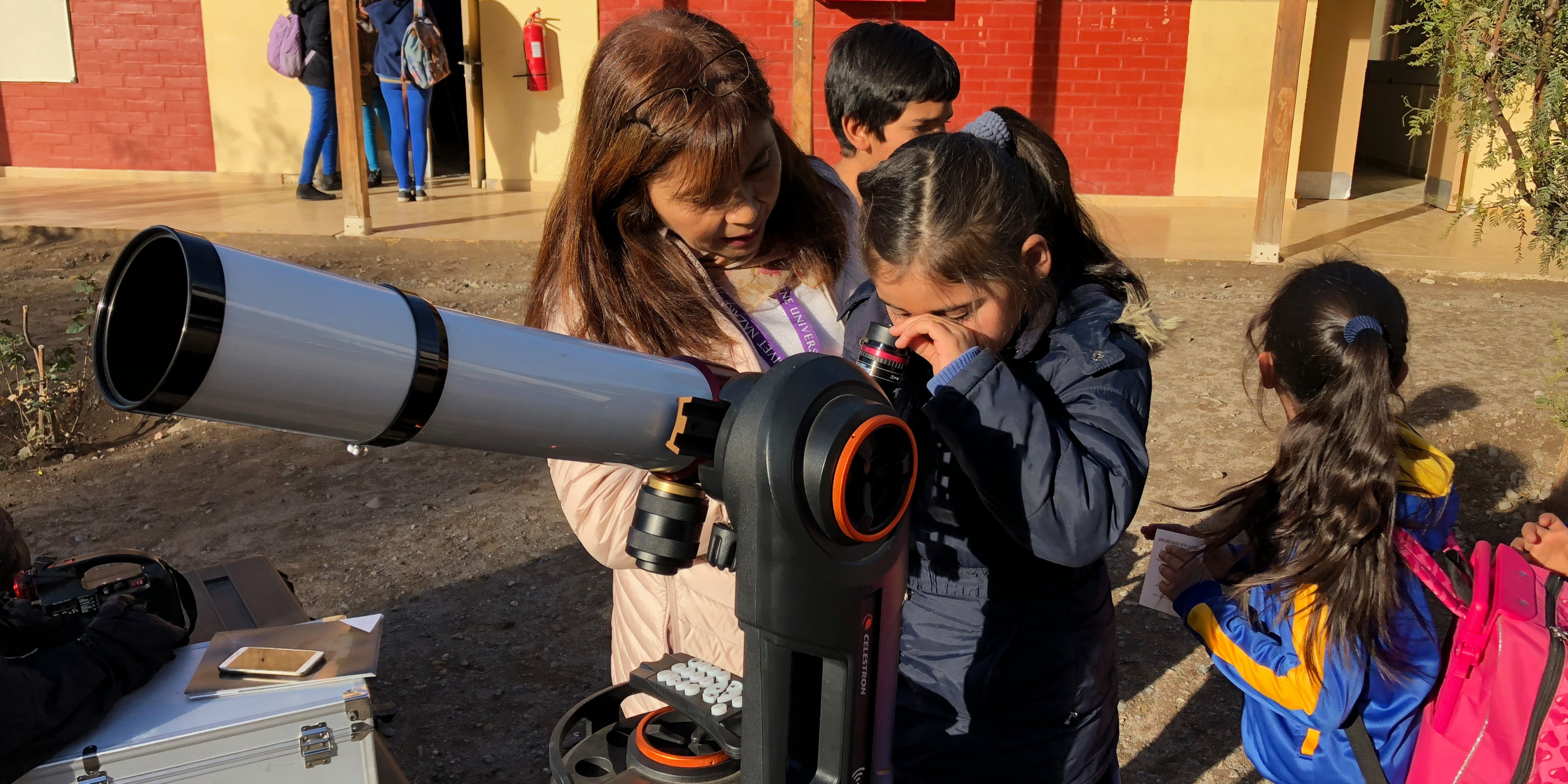 Mentor guides a student using a telescope