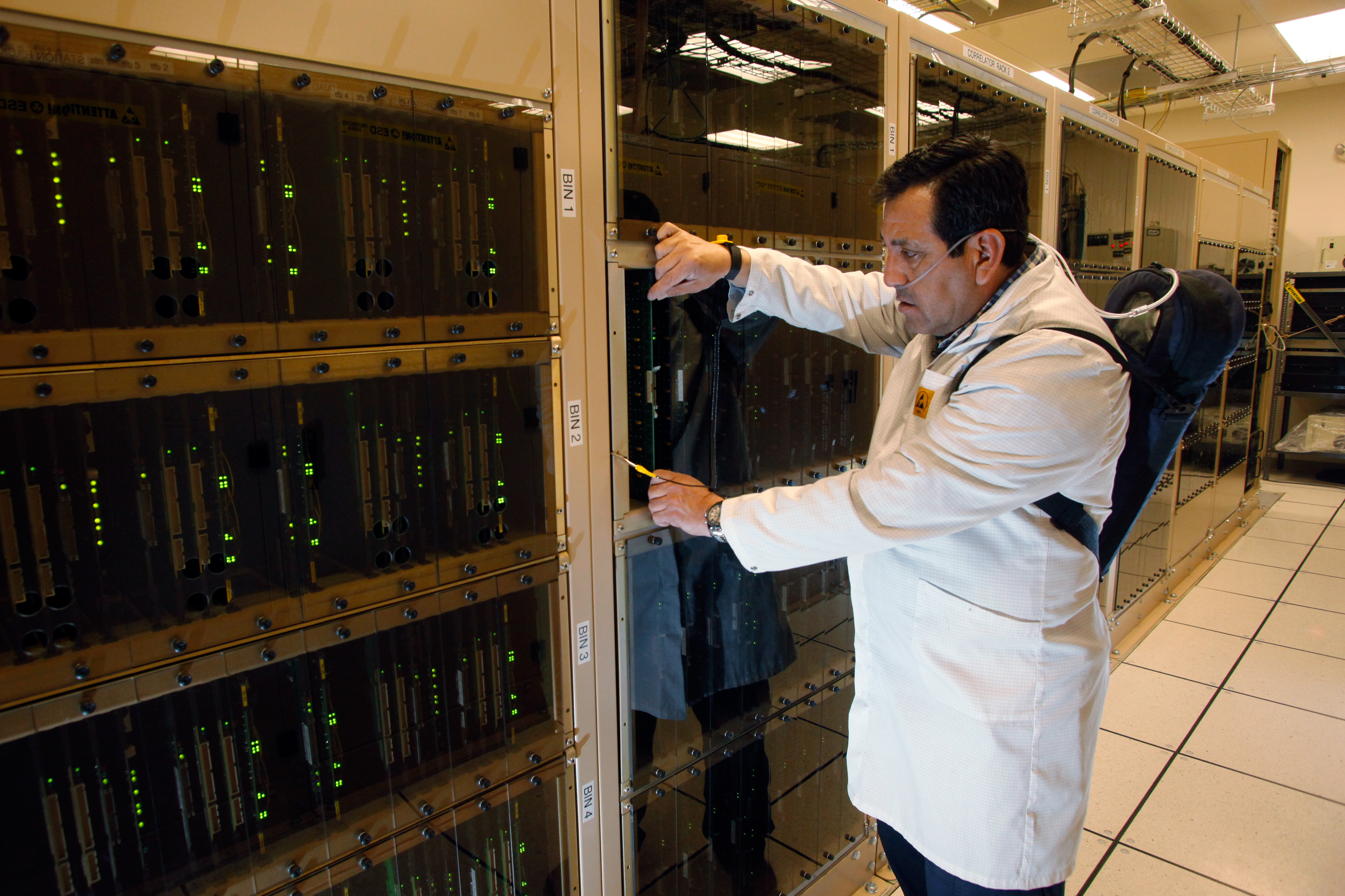 Technician  Juan Carlos Gatica checks electronics on the ALMA correlator. 