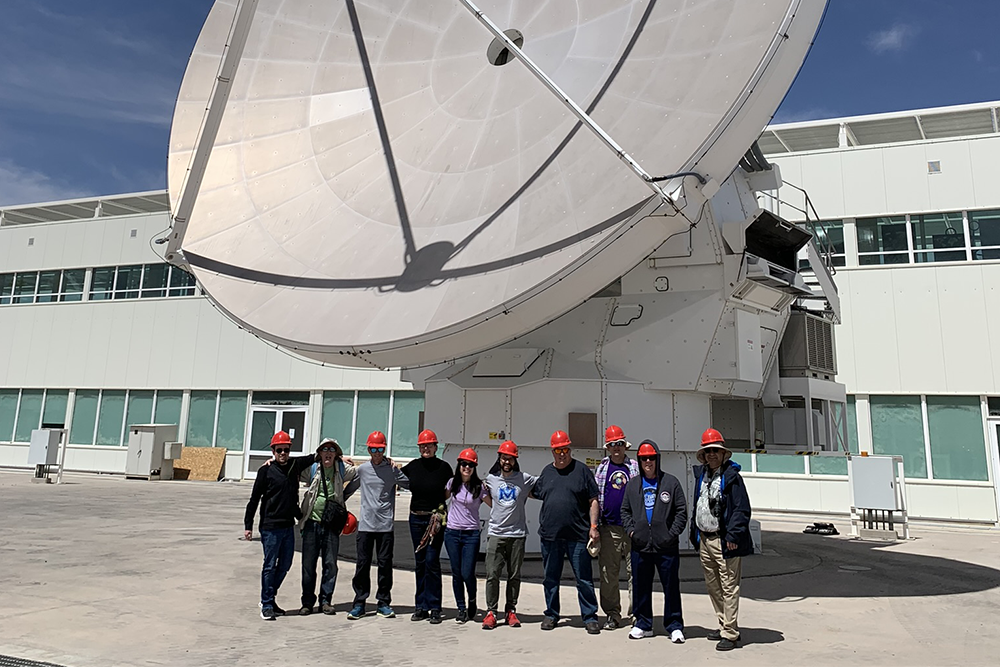 ACEAP 2020 cohort stands in front of a radio telescope at ALMA
