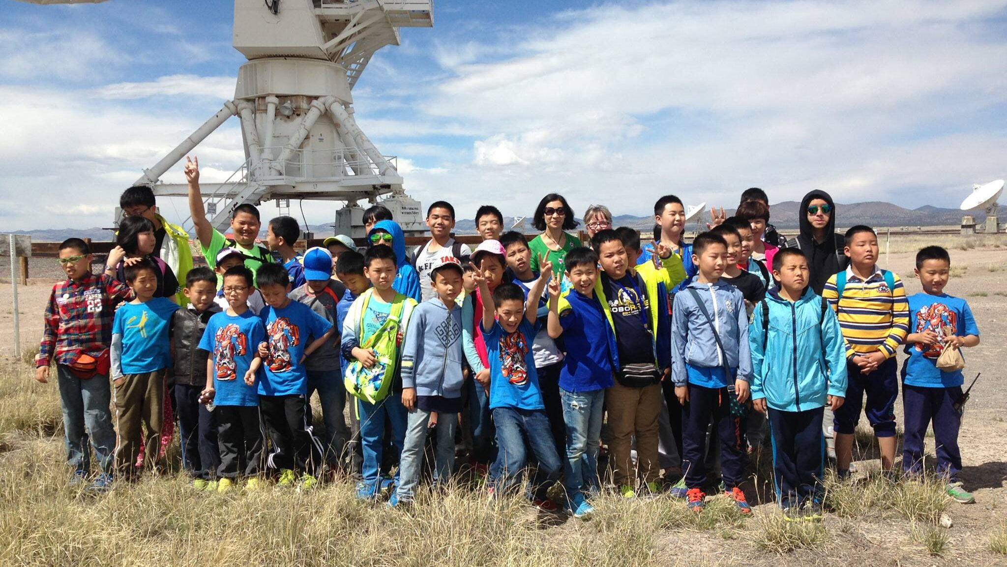 A group of Chinese students gather in front of an antenna of the VLA
