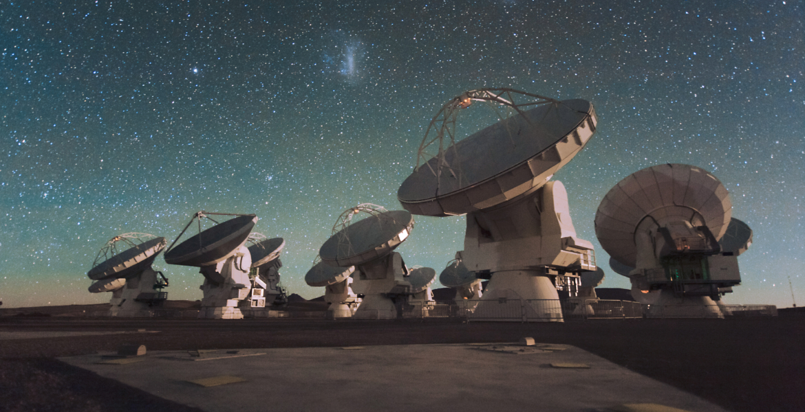 Antennas of the Atacama Large Millimeter/submillimeter Array (ALMA), on the Chajnantor Plateau in the Chilean Andes. The Large and Small Magellanic Clouds, two companion galaxies to our own Milky Way galaxy, can be seen as bright smudges in the night sky, in the center of the photograph.