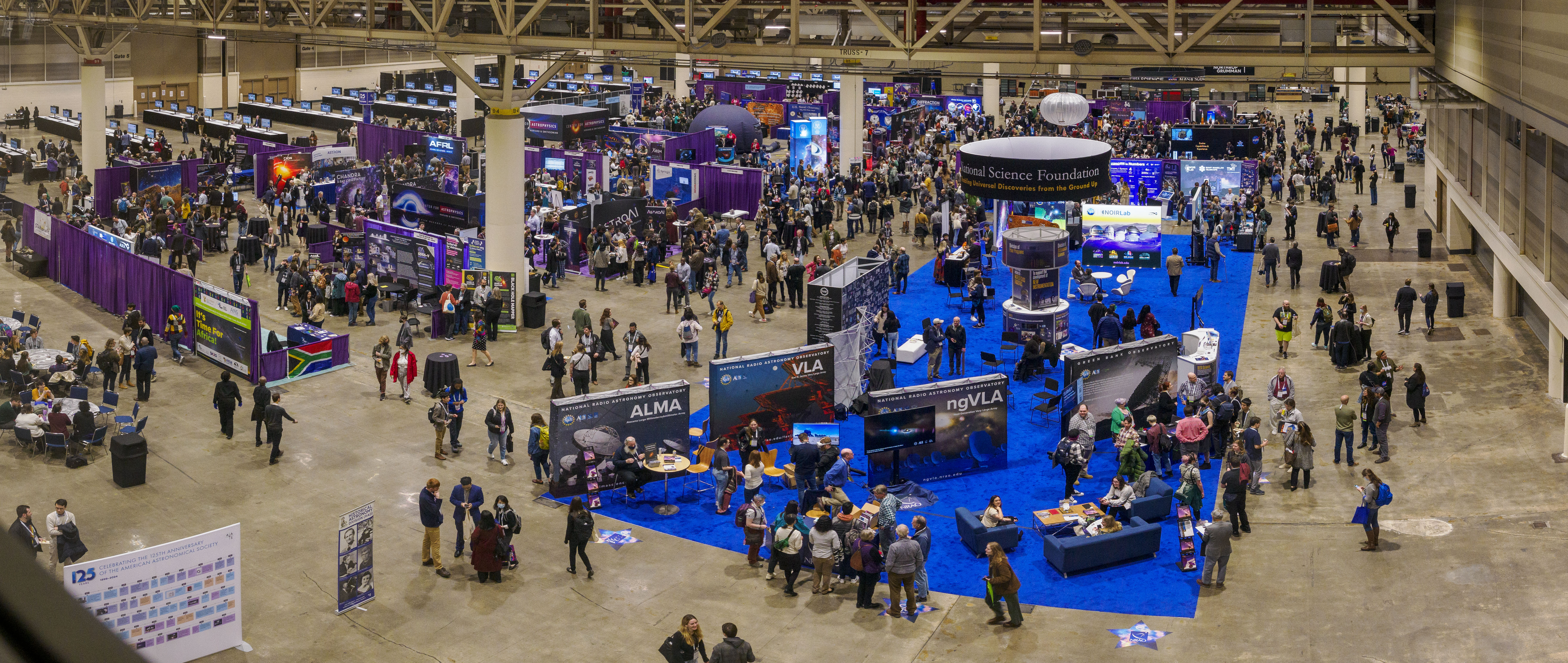 Arial view of exhibit hall full of booths and attendees at the AAS 243 conference.