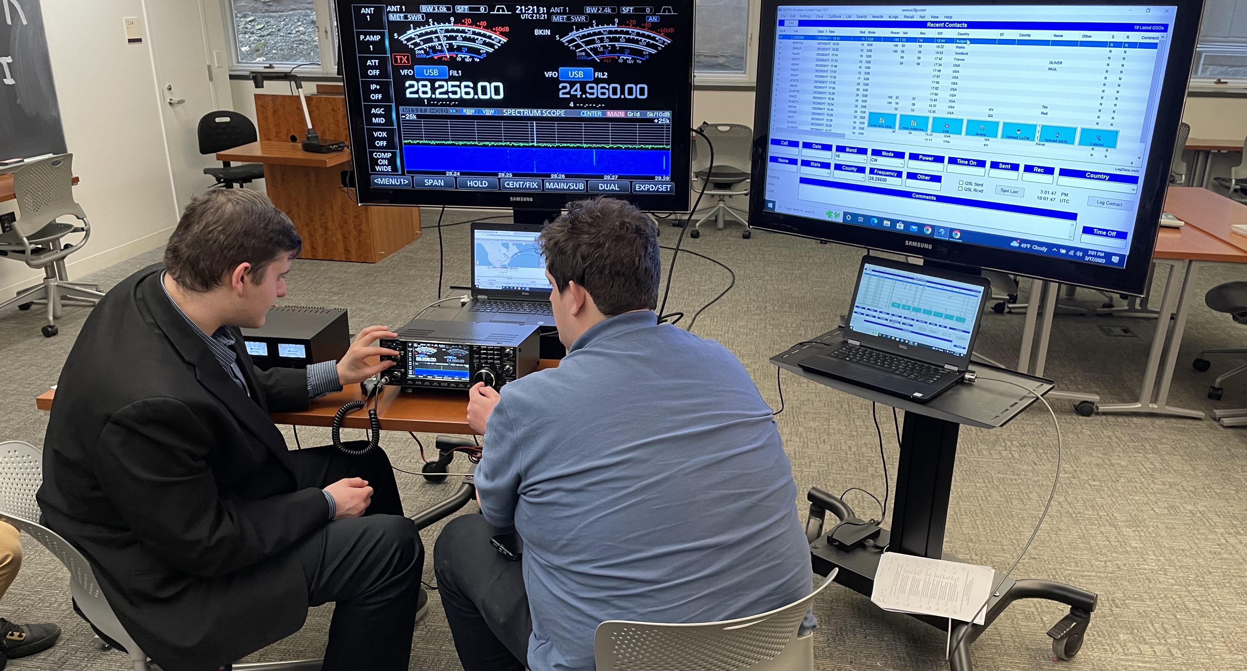 Two students sit at a table and operate a Ham radio.