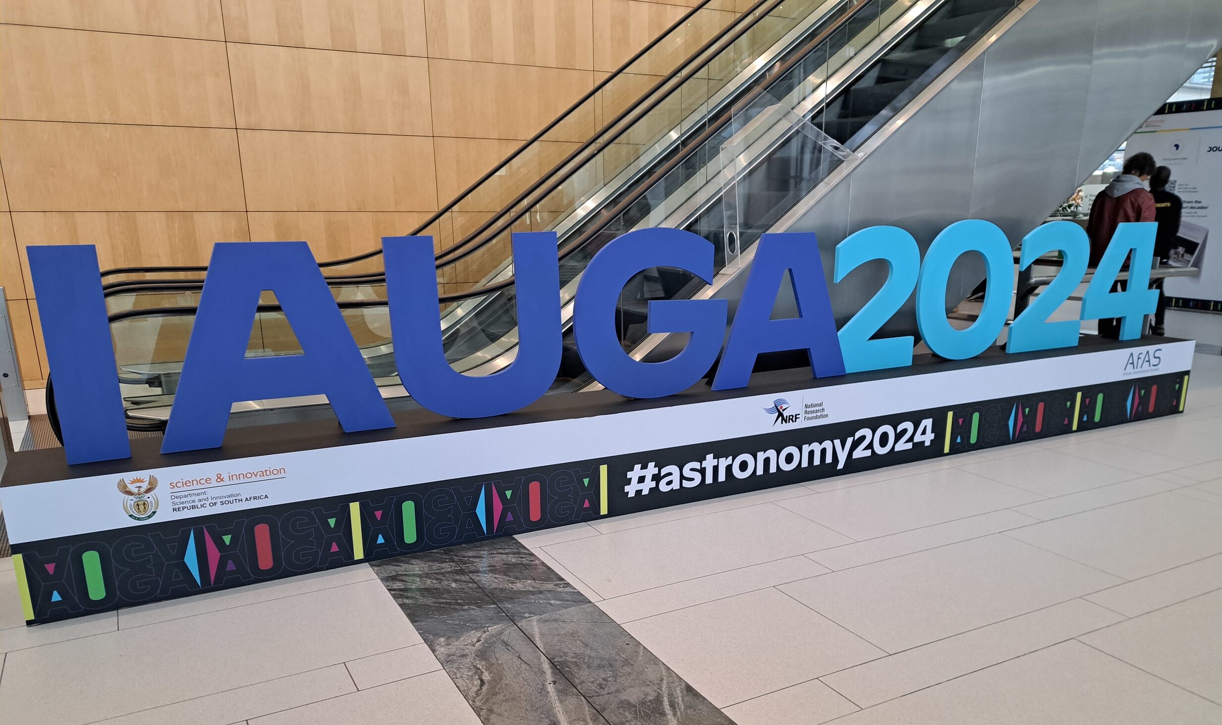 Large, blue 3D sign that reads, "IAU GA 2024".