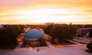 The sun sets behind an observatory dome.