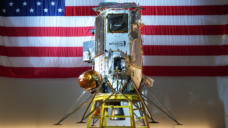 Intuitive Machines' IM-2 mission Nova-C lunar lander, Athena, standing in front of an American flag in the company's Lunar Production and Operations Center.