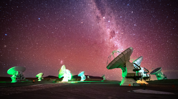 Milky Way Galaxy illuminated in a purple hue shines over ALMA antennas 