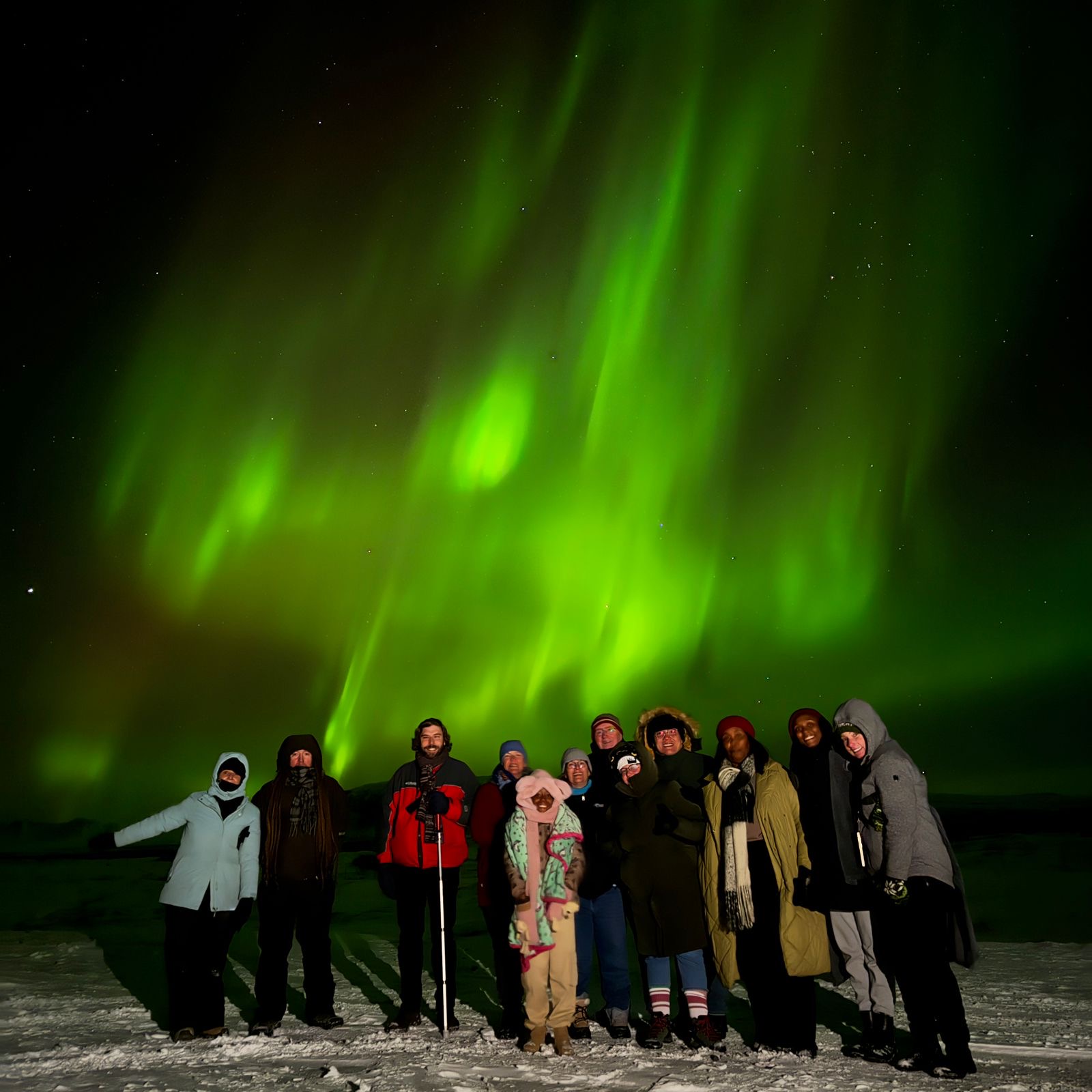 Astro Accel members stand under green ribbons of the Aurora Borealis