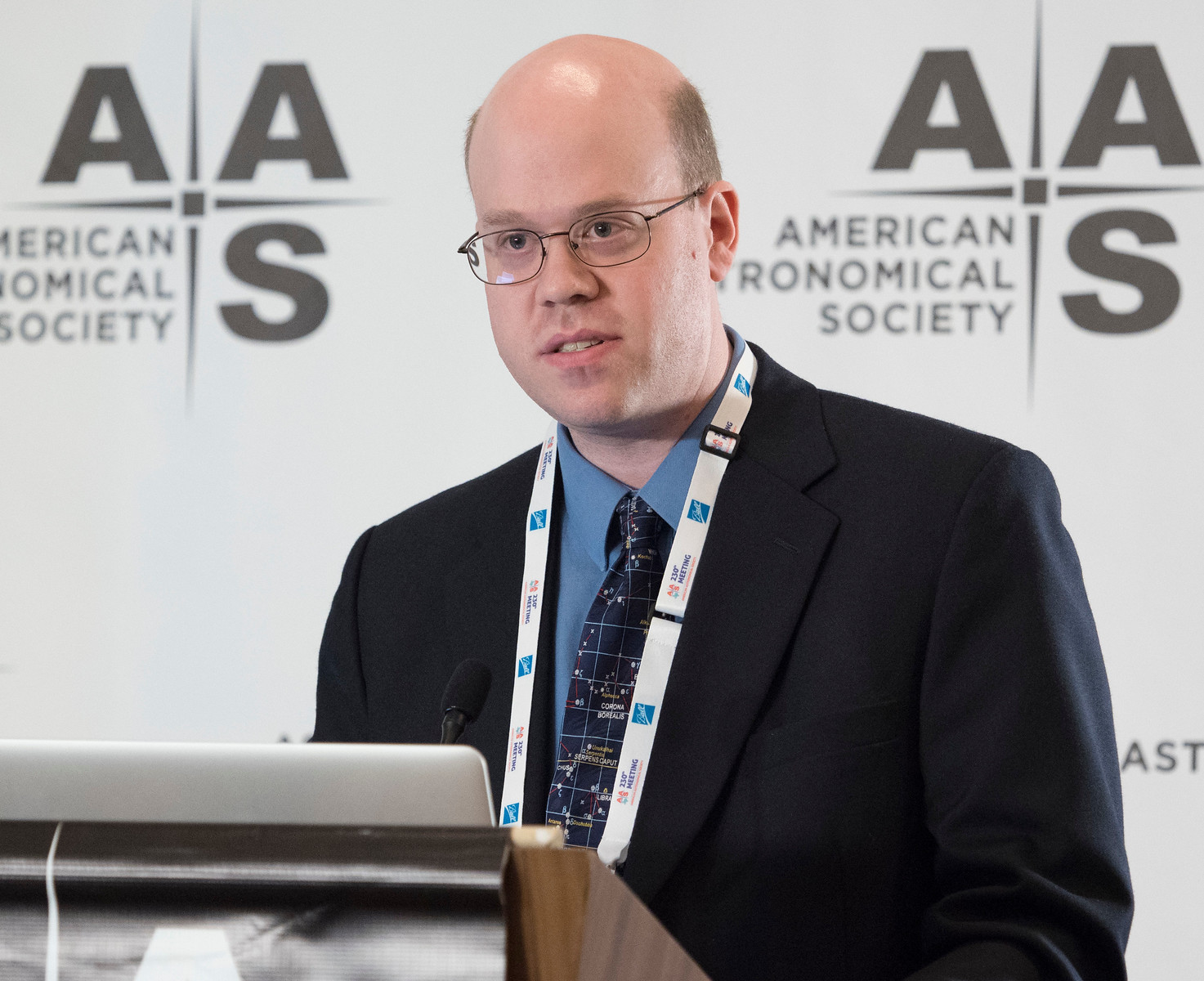 Brian Kent speaks behind a podium at a AAS conference.