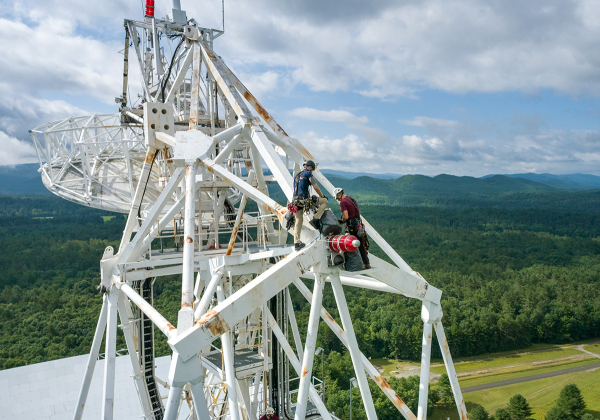 Two maintenance workers work on the Green Bank Telescope's feed arm