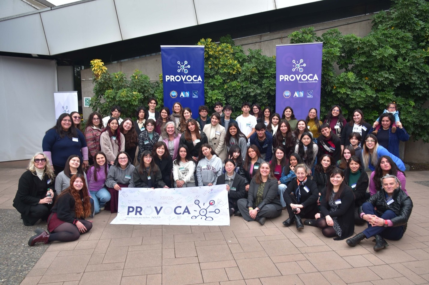 A cohort of PROVOCA student gather together around a sign with the program's name.